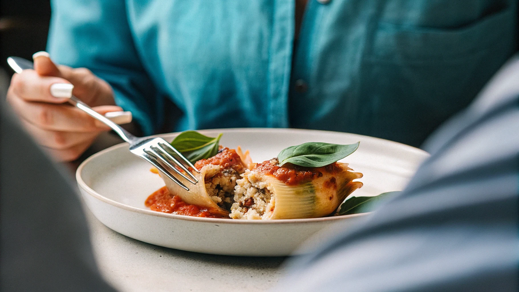 Plated stuffed shells with basil and marinara on a dinner table